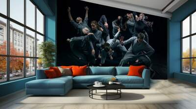 Group of young men and women contemp dancers performing against black studio background. Concept of modern freestyle dance, contemporary art, movements, hobby and creative lifestyle Wall mural