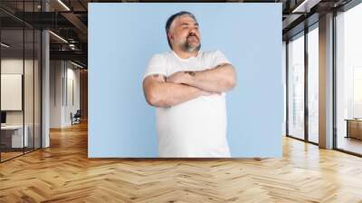 Handsome caucasian plus size male model isolated on blue studio background. Concept of inclusion, human emotions, facial expression Wall mural