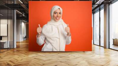 Happy arab woman in hijab. Portrait of smiling girl, posing at red studio background. Young emotional woman. The human emotions, facial expression concept. Front view. Wall mural