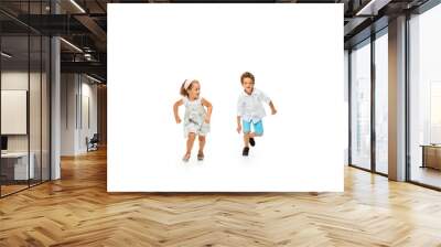 Happy children, little and emotional caucasian boy and girl jumping and running isolated on white background. Look happy, cheerful, sincere. Copyspace for ad. Childhood, education, happiness concept. Wall mural