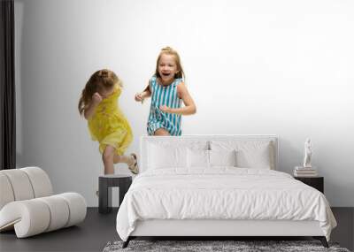 Happy children, little and emotional caucasian girls jumping and running isolated on white background. Looks happy, cheerful, sincere. Copyspace for ad. Childhood, education, happiness concept. Wall mural