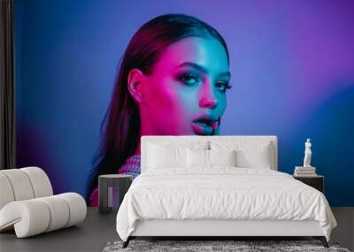 High fashion model in colorful bright neon lights posing at studio. Portrait of beautiful girl with trendy glowing make-up. Art design vivid style. Wall mural