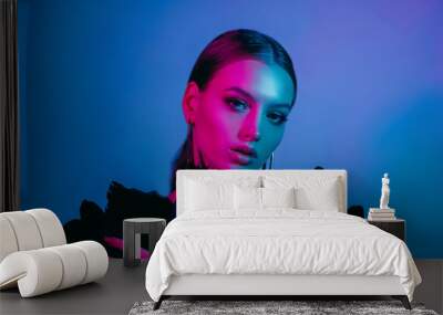 High fashion model in colorful bright neon lights posing at studio. Portrait of beautiful girl with trendy glowing make-up. Art design vivid style. Wall mural