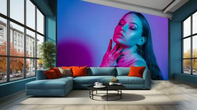 High fashion model in colorful bright neon lights posing at studio. Portrait of beautiful girl with trendy glowing make-up. Art design vivid style. Wall mural