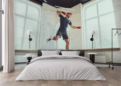 Kick in jump. Young caucasian man training at home during quarantine of coronavirus outbreak, doing exercises of fitness, box. Staying sportive during insulation. Wellness, sport, movement concept. Wall mural