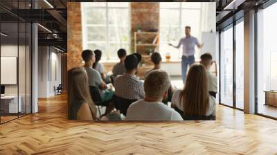 Male speaker giving presentation in hall at university workshop. Audience or conference hall. Rear view of unrecognized participants in audience. Scientific conference event, training. Education Wall mural