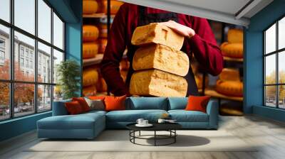 Man holding cheese brocks in specials place for cheese storage and production. Eco food. Aged cheese. Concept of food, taste, art of organic products, healthy, natural food. Wall mural