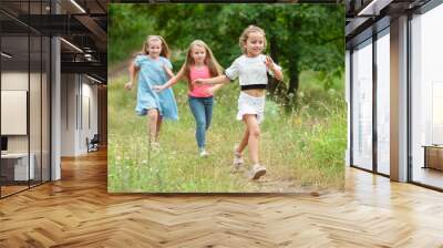 Memories. Kids, children running on green forest. Cheerful and happy boys and girs playing, laughting, running through green blooming meadow. Childhood and summertime, sincere emotions concept. Wall mural