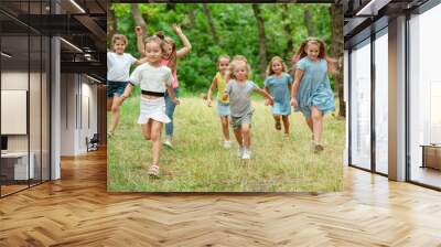 Memories. Kids, children running on green forest. Cheerful and happy boys and girs playing, laughting, running through green blooming meadow. Childhood and summertime, sincere emotions concept. Wall mural