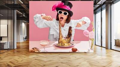 Passionate eater. Emotinal woman in cylinder hat and suglasses eating spaghetti with chocolate sauce against pink background. Gourmet. Concept of pop art, creativity, food, inspiration, emotions Wall mural