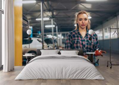 Portrait of young confident girl wearing working clothes standing at auto service station, indoors. Gender equality. Emotions, work, occupation, fashion, job and hobby Wall mural