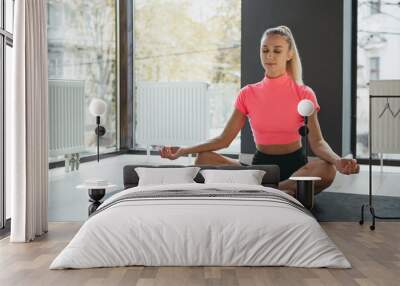 Portrait of young slim sportive woman in sportswear doing yoga exercise on sports mat at yoga meditation center. Concept of healthy lifestyle, wellbeing, mental health Wall mural