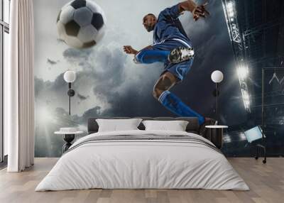 Professional football or soccer player in action on stadium with flashlights, kicking ball for winning goal, wide angle. Concept of sport, competition, motion, overcoming. Field presence effect. Wall mural