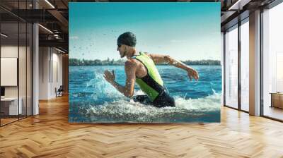 Professional triathlete swimming in river's open water. Man wearing swim equipment practicing triathlon on the beach in summer's day. Concept of healthy lifestyle, sport, action, motion and movement. Wall mural