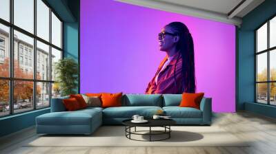 Profile view of young girl with afro hairdo in cotton shirt isolated on purple background in neon light. Concept of beauty, art, fashion, youth and emotions Wall mural