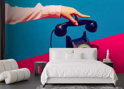 Retro objects, gadgets. Female hand holding handset of vintage phone isolated on blue and pink background. Vintage, retro fashion style. Pop art photography. Wall mural