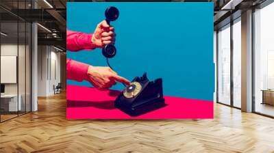 Retro objects, gadgets. Female hand holding handset of vintage phone isolated on blue and pink background. Vintage, retro fashion style. Pop art photography. Wall mural