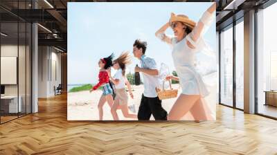 Running down the beach. Seasonal feast at beach resort. Group of friends celebrating, resting, having fun in sunny summer day. Look happy and cheerful. Festive time, wellness, holiday, party. Wall mural