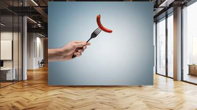 sausage on a fork in his hand Wall mural