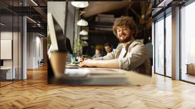 Senior developer. Happy man looking at camera and smilling. Work in modern loft style office using devices and gadgets during job processing. Wall mural