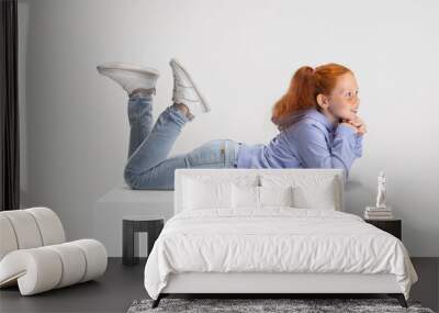 Side view. Portrait of smiling red-headed girl in casual clothes isolated on white studio background. Happy childhood concept. Sunny child. Looks happy, delighted Wall mural