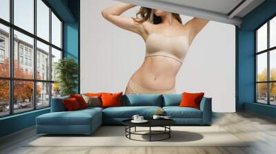 Slim sportive young woman in underwear on grey background. Fitness, diet, skin and body care. Wall mural