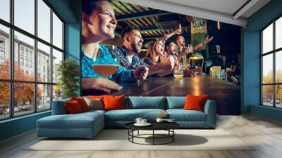 Sport, people, leisure, friendship and entertainment concept - happy football fans or male friends drinking beer and celebrating victory at bar or pub Wall mural