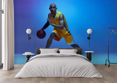 Sportive athletic african-american male basketball player training in neon light on blue background. Wall mural