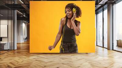 Studio portrait of adorable curly girl happy smiling during photoshoot. Stunning african woman with light-brown skin relaxing in headphones Wall mural