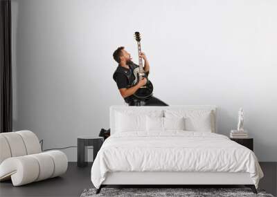 Stylish musician wearing retro style clothes playing guitar like rockstar isolated on white background. Retro style, vintage fashion, music, art Wall mural