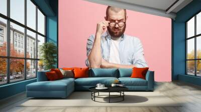 Suspiciont. Doubtful man with thoughtful expression making choice against pink background Wall mural