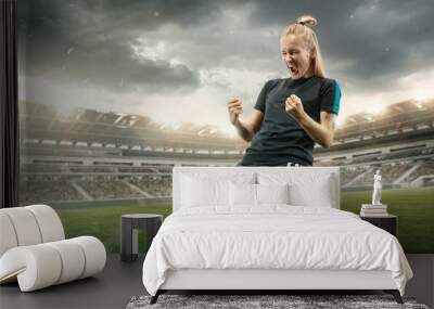 Taste or win. Young female soccer or football player in sportwear celebrating the goal in action at the stadium while gameplay. Concept of healthy lifestyle, professional sport, hobby, motion Wall mural