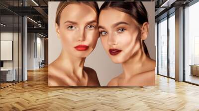 Tender youth. Portrait of two young, beautiful girls with red lips makeup isolated over grey studio background. Shadows. Concept of skincare, cosmetology, natural beauty Wall mural