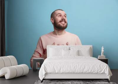 The happy business man standing and smiling against blue background. Wall mural