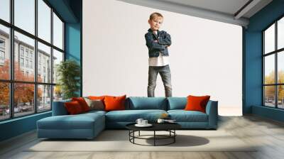 the portrait of cute little kid boy in stylish jeans clothes looking at camera against white studio  Wall mural