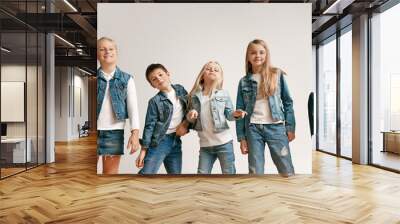 the portrait of cute little kids boy and girls in stylish jeans clothes looking at camera against wh Wall mural