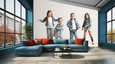 The portrait of cute little kids boy and girls in stylish jeans clothes looking at camera against white studio wall. Kids fashion and happy emotions concept Wall mural