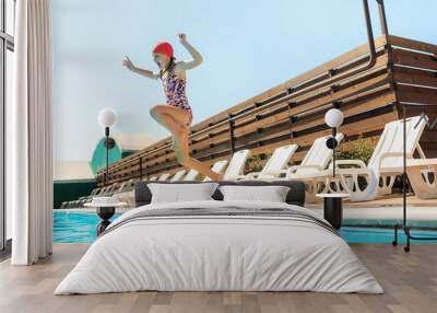 The portrait of happy smiling beautiful teen girl jumping at the swimming pool. Little child at blue wate. Pool, leisure, swimming, summer, recreation, healthy lifstyle concept Wall mural