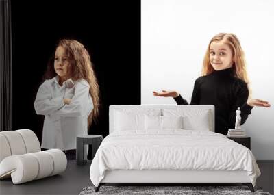 The portrait of two emotional happy surprised girl and sad serious girl on a white and black studio background. Human emotions concept. Comparison of different emotions. The childhood, kid, friendship Wall mural