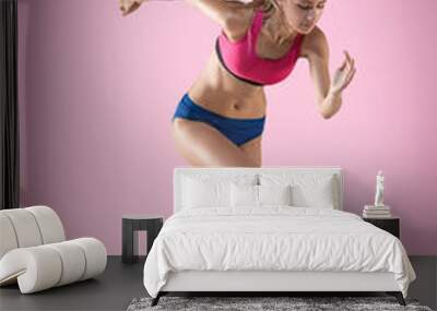 The studio shot of high jump athlete or fit woman in action i on pink background Wall mural