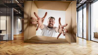 The surprised man unpacking, opening carton box and looking inside. The package, delivery, surprise, gift lifestyle concept. Human emotions and facial expressions concepts Wall mural