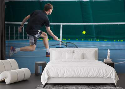 The young man in a closed tennis court with ball Wall mural