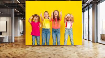 Thumbs up. Happy children playing and having fun together on yellow studio background. Caucasian kids in bright clothes looks playful, laughting, smiling. Concept of education, childhood, emotions. Wall mural