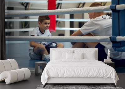 Two athletes, son and father is doing sports in gym. Beginner boxer workout with his coach ar boxing ring, indoors. Sport, power, energy and active lifestyle Wall mural