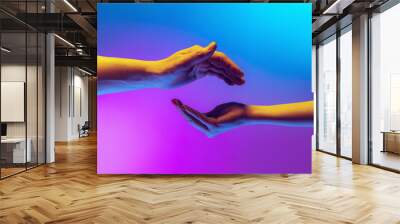 Two authentic hands trying to touch each other isolated on gradient blue purple background in neon light. Concept of relationship, community, care, support, symbolism, culture Wall mural