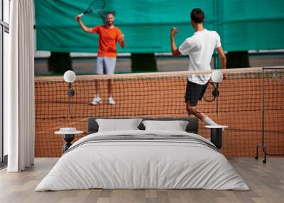 Two men, friends, tennis player showing gesture of victory after intense winning game, match on outdoor clay court. Team. Concept of sport, competition, active and healthy lifestyle Wall mural