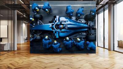 View from above, car receives rapid servicing from dedicated pit crew in blue gear. Coordination and efficiency required to maintain competitive edge in racing. Wall mural