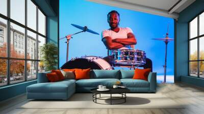 young african-american jazz musician or drummer playing drums on blue studio background in trendy ne Wall mural