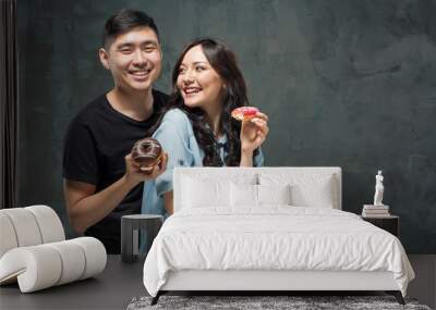 Young asian couple enjoy eating of sweet colorful donut Wall mural