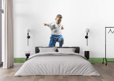 Young boy with soccer ball running and jumping isolated on white studio background. Junior football soccer player in motion Wall mural